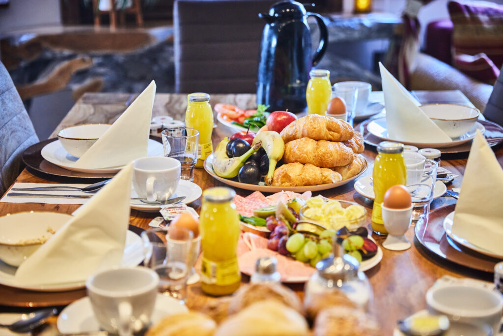 Hirschmeier-Media_20240920_00005 - WaveCult gedeckter Frühstückstisch mit Croissant Brötchen Ei Saft Obst Wurst und Käse im Strandhotel am Steinhuder Meer Eventgastronomie